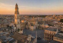 Illustrazione realistica generata con intelligenza artificiale della Piazza del Duomo di Lecce al tramonto, con la Cattedrale e il campanile in stile barocco.